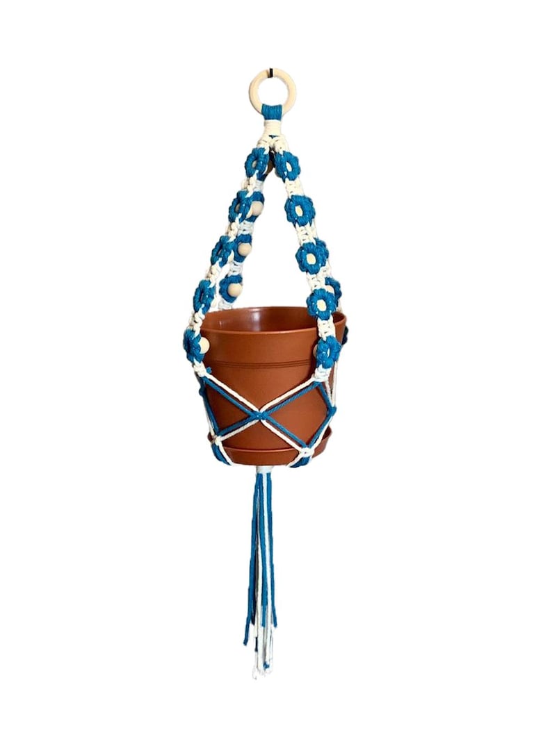 Peut inclure: Un porte-plante en macram&eacute; blanc et turquoise avec des perles en bois et un pot en terre cuite.