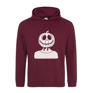 Op de afbeelding: Een bordeauxrode hoodie met een witte afbeelding van een pompoen met een gezicht. De pompoen heeft een gestikte mond en druipende ogen.