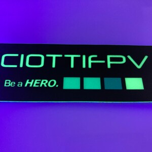 May include: A black and green glow-in-the-dark sticker with the text "CIOTTIFPV" and "Be a HERO." The sticker has five green squares.