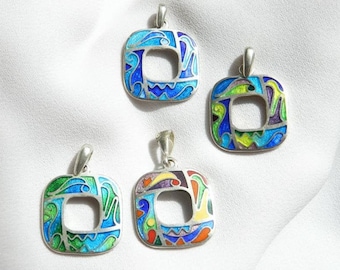 Puede incluir: Cuatro colgantes de plata con diseños de esmalte de colores. Cada colgante tiene forma cuadrada con un recorte en el centro. Los diseños de esmalte presentan una variedad de colores, incluyendo azul, verde, amarillo, rojo y morado.