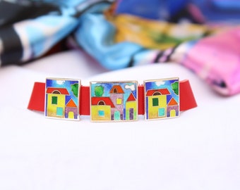 Puede incluir: Tres pulseras de plata con casas de esmalte de colores en una banda de cuero roja.