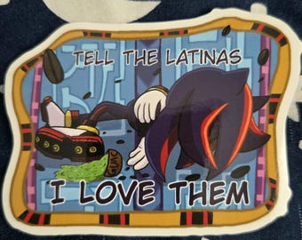 May include: A sticker featuring a cartoon character with black and red fur, lying down. The sticker has the text "TELL THE LATINAS I LOVE THEM" in white letters. The sticker has a gold border and is on a blue background.