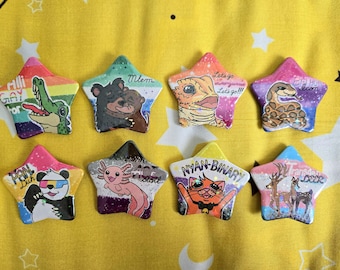 Puede incluir: Ocho insignias en forma de estrella con ilustraciones de animales. Los diseños incluyen un cocodrilo, un oso, un lagarto, una serpiente, un panda, un ajolote, un gato y un ciervo. Algunas insignias tienen texto como "GAY", "Mlem" y "NYAN-BINARY".