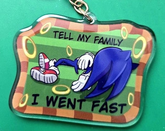 Puede incluir: Un llavero de acrílico azul y blanco con un personaje de dibujos animados acostado con el texto "Tell my family I went fast".