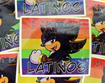 Puede incluir: Pegatina con un personaje de dibujos animados en negro y azul, sobre un fondo de arcoíris. Se muestra el texto "I JUST LOVE LATINOS". Otras pegatinas son visibles en el fondo.