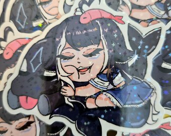 Puede incluir: Una colección de pegatinas con un personaje de dibujos animados con pelo negro, un uniforme de marinero azul y un pez rosa en la cabeza. Las pegatinas tienen un acabado holográfico y brillante.
