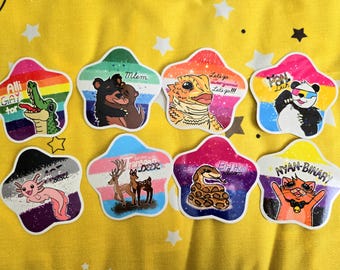 Puede incluir: Una colección de ocho pegatinas en forma de estrella con ilustraciones coloridas de animales y texto. Las pegatinas presentan una variedad de diseños, incluyendo un caimán, osos, un lagarto, un panda, un ajolote, ciervos, una serpiente y un gato.