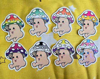 Puede incluir: Una colección de ocho pegatinas de hongos coloridos. Cada pegatina presenta un personaje de hongo sonriente con un sombrero de diferentes patrones, incluyendo arcoíris y lunares. Las pegatinas están sobre un fondo amarillo.