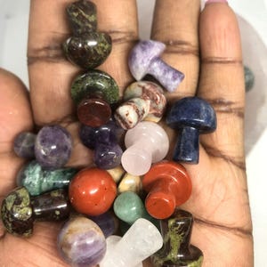 May include: A collection of small, polished gemstone mushroom figurines in various colours, including green, purple, red, blue, and white.