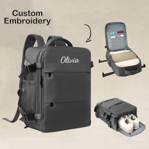 Puede incluir: Una mochila gris con el nombre "Olivia" bordado en la parte delantera. La imagen muestra los compartimentos de la mochila, incluido un compartimento para zapatos y una sección para ropa y accesorios. El texto "Custom Embroidery" está en la parte superior.