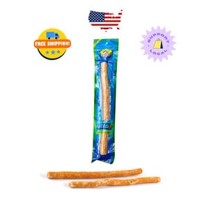 May include: A package of Miswak natural toothbrushes, with three additional toothbrushes lying below. The toothbrushes are light brown and packaged in a green and blue plastic wrapper. The packaging has the word "Miswak" printed on it.