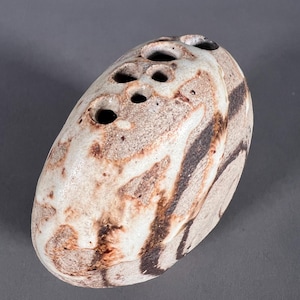 May include: A white ceramic vase with brown and black glaze. The vase has a rounded shape and multiple holes for flowers.