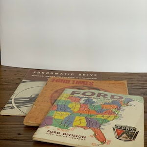 May include: Three vintage Ford publications: a pamphlet titled "Fordomatic Drive", a magazine titled "Ford Times", and a map of the United States with the text "Ford Division Ford Motor Company".