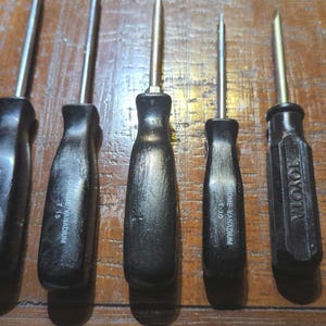 Könnte beinhalten: Sechs schwarze Schraubendreher mit Chrom-Vanadium-Griffen. Die Schraubendreher haben verschiedene Größen, darunter 1/20, 7/16, 1/8, 1/16 und 1/32. Ein Schraubendreher hat den Schriftzug "TOYOTA" auf dem Griff.