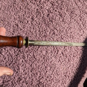 May include: A wooden handled steel knife sharpener with a brass ring.