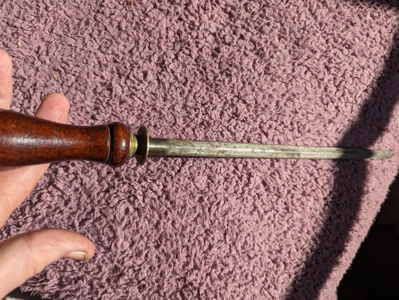May include: A wooden handled steel knife sharpener with a brass ring.