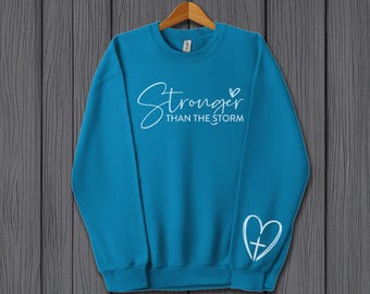 Sudadera "Más fuerte que la tormenta" / Prenda inspiradora con diseño de cruz en forma de corazón en las mangas / Regalo inspirador para mujeres de fe