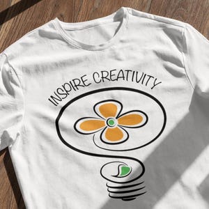 Camiseta "Inspira la creatividad", camiseta con el logotipo de una flor y una bombilla artística, camiseta gráfica para creadores y artistas.