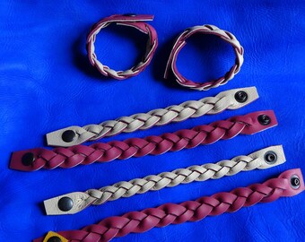 May include: Five braided leather bracelets in two colors: burgundy and beige. The bracelets have black snap closures.