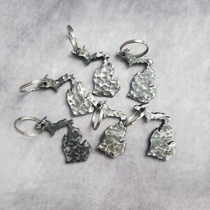 Puede incluir: Seis llaveros de plata con forma del estado de Michigan. Cada llavero tiene una textura martillada y un anillo de llave de plata.
