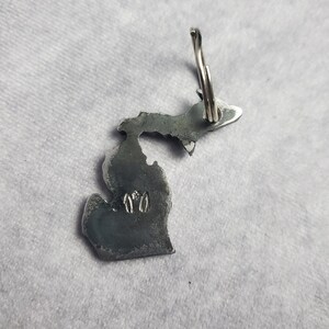 Puede incluir: Un llavero de metal plateado con forma del estado de Michigan. El llavero tiene un anillo en la parte superior y el n&uacute;mero "170" est&aacute; grabado en la parte inferior del estado.