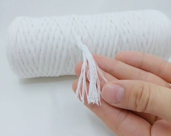 Könnte beinhalten: Ein weißes Baumwollseil mit einem Quasten am Ende. Das Seil ist aufgerollt und wird von einer Hand gehalten.