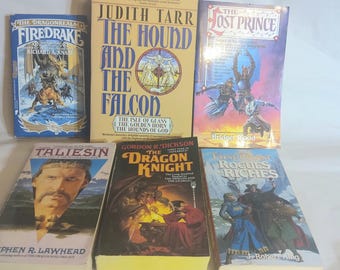 May include: A collection of fantasy novels with colorful covers. Titles include "The Hound and the Falcon," "The Lost Prince," and "The Dragon Knight." The books are arranged on a white surface, showcasing their unique cover art and titles.