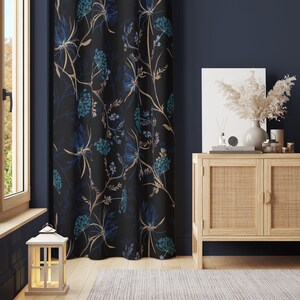 Può includere: Una tenda nera con un motivo floreale blu e oro è appesa davanti a un muro blu scuro. Un mobile in legno con ante intrecciate si trova davanti alla tenda. Un vaso con fiori secchi è posto sopra il mobile.