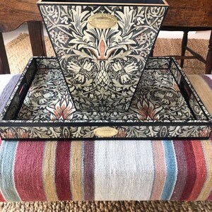 May include: A black and white tray with a floral design and a gold label that says "Made in England, Dorothea Harrison, Est. 1936". The tray is sitting on top of a black and white patterned wastebasket.