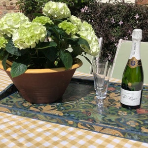 May include: A decorative tray with a floral design holds a potted hydrangea with light green blooms, two champagne flutes, and a bottle of Pol Roger champagne. The tray sits on a yellow and white checkered tablecloth.