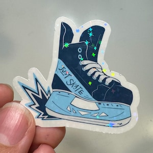 Könnte beinhalten: Ein blauer und weißer Schlittschuh-Aufkleber mit Glitzerakzenten. Der Schlittschuh trägt den Schriftzug "Just Skate" an der Seite.