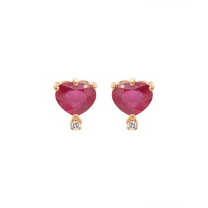 May include: A pair of gold heart-shaped earrings with red ruby gemstones and a small diamond accent.