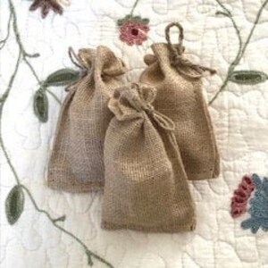 May include: Three small burlap bags with drawstrings. The bags are a light brown color and are made of a natural material.