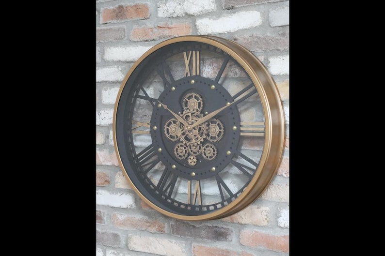 May include: A large, round wall clock with a steampunk design. The clock features a black face with gold-colored gears and Roman numerals. The frame is gold-colored, and the clock is mounted on a brick wall.