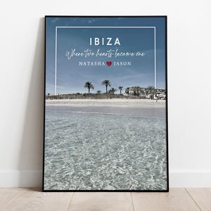 May include: A black framed print with a photo of a beach in Ibiza, Spain. The text "IBIZA Where two hearts became one NATASHA ♥ JASON" is printed on the image.