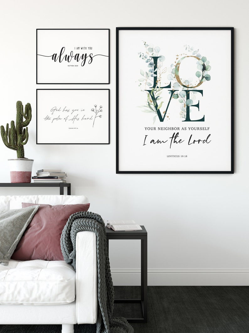 Op de afbeelding: Drie ingelijste prints met inspirerende citaten en bloemmotieven. De bovenste print zegt "Ik ben altijd bij je" met een handschrift. De middelste print zegt "God heeft je in de palm van zijn hand". De onderste print heeft een grote groene en gouden "LOVE" met de quote "Heb je naaste lief als jezelf Ik ben de Heer" en de bijbelverwijzing "Leviticus 19:18".