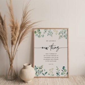 May include: A framed print with a watercolor background of green leaves and the text "SEE, I AM DOING A new thing NOW IT SPRINGS UP. DO YOU NOT PERCEIVE IT? I AM MAKING A WAY IN THE WILDERNESS AND STREAMS IN THE WASTELAND. ISAIAH 43:19"