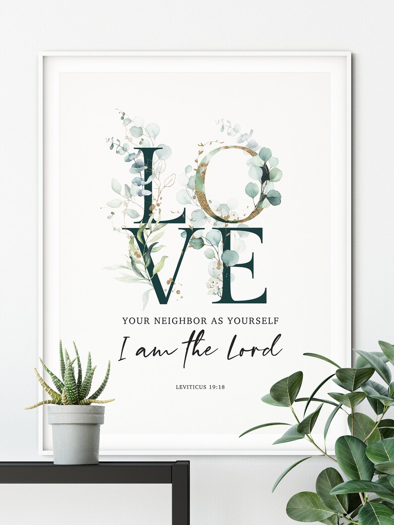Op de afbeelding: Een witte ingelijste print met een groen en gouden bloemendesign dat het woord "LOVE" spelt. De tekst "Your neighbor as yourself I am the Lord" staat onder het bloemendesign, met de bijbelverwijzing "Leviticus 19:18" eronder.