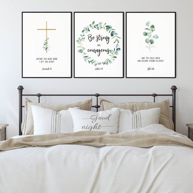 May include: Three framed prints with white backgrounds and black frames. The prints feature watercolor illustrations of eucalyptus leaves and gold lettering with bible verses. The verses are "Before you were born I set you apart" from Jeremiah 1:5, "Be strong and courageous" from Joshua 1:9, and "And the child grew and became strong in spirit" from Luke 2:40.