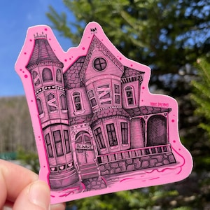 May include: Pink sticker of a spooky, detailed, black and white illustration of a haunted house with a sign that says "Beware".