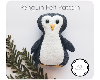 May include: A black and white felt penguin pattern for sewing a stuffed toy. The pattern is available as a PDF download. The penguin has a yellow beak and black eyes.