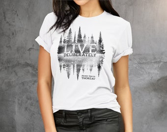 May include: White t-shirt with a black and white graphic print of a forest with the text "LIVE DELIBERATELY" and "HENRY DAVID THOREAU" underneath.