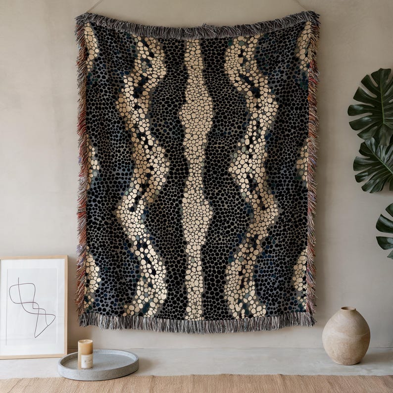 Peut inclure: Une couverture tiss&eacute;e avec un motif r&eacute;p&eacute;titif de points noirs et cr&egrave;me et de rayures verticales. La couverture a un bord &agrave; franges et est accroch&eacute;e &agrave; un mur. La palette de couleurs comprend le noir, la cr&egrave;me et le bleu.