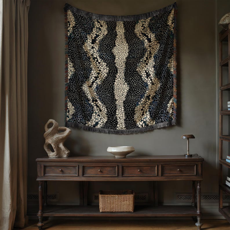 Peut inclure: Une tenture murale sombre &agrave; motifs, avec une bordure &agrave; franges, est suspendue au-dessus d'une console en bois. La tenture pr&eacute;sente un motif r&eacute;p&eacute;titif de formes bleu fonc&eacute;, beige et blanches. La console a trois tiroirs et une &eacute;tag&egrave;re inf&eacute;rieure avec un panier tress&eacute;.