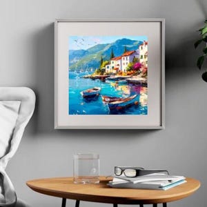 May include: Framed art print of a coastal scene with boats, buildings, and mountains. The artwork features a vibrant color palette of blues, greens, and whites, with a focus on the water and the architecture. The painting is displayed on a gray wall.