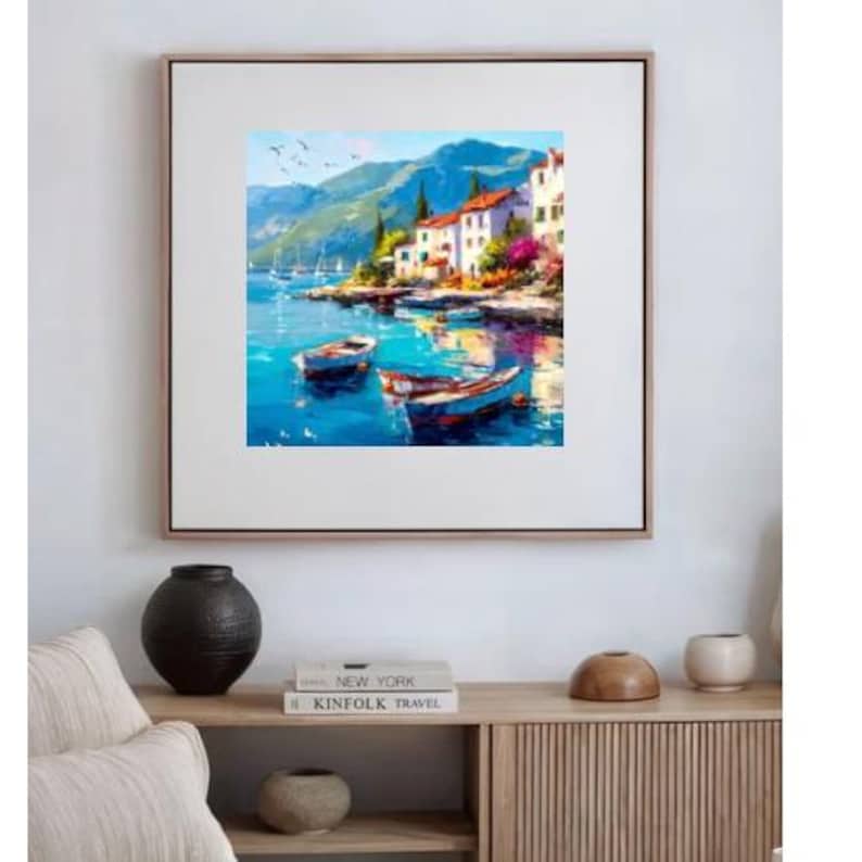 May include: Oil painting of a coastal scene with boats, buildings, and mountains. The artwork features a vibrant color palette of blues, greens, and whites. Two small boats float on the water, and buildings with red tile roofs line the shore.