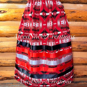 Pode incluir: Uma saia vermelha com um padr&atilde;o geom&eacute;trico em preto, branco e cinza. A saia tem um c&oacute;s el&aacute;stico e &eacute; decorada com fitas horizontais em preto, vermelho e prata perto da bainha. O texto AteedSneezCreations &eacute; vis&iacute;vel na imagem.