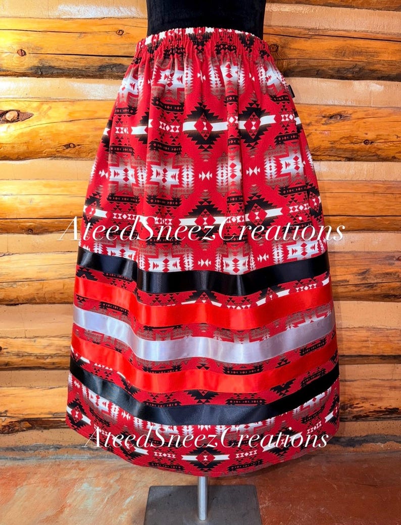 Pode incluir: Uma saia vermelha com um padr&atilde;o geom&eacute;trico em preto, branco e cinza. A saia tem um c&oacute;s el&aacute;stico e &eacute; decorada com fitas horizontais em preto, vermelho e prata perto da bainha. O texto AteedSneezCreations &eacute; vis&iacute;vel na imagem.