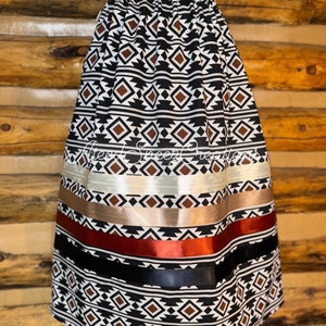 Pode incluir: Uma saia at&eacute; o joelho com um padr&atilde;o geom&eacute;trico repetitivo de diamantes em preto, branco e marrom. A saia inclui detalhes de fitas de cetim horizontais em creme, bege, cobre e preto. O texto "Alesa Sheep Creations" e "Aztec Design" est&aacute; presente.