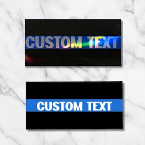 May include: Two black rectangular stickers with the words "CUSTOM TEXT" printed on them. The top sticker has a holographic stripe with the text in silver. The bottom sticker has a blue stripe with white text.